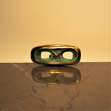 Artistic shot of an oblong bronze cufflink on marble that looks like sculpture.